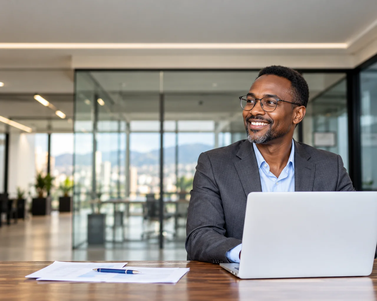 A business owner smiling behind a laptop in a bright office.